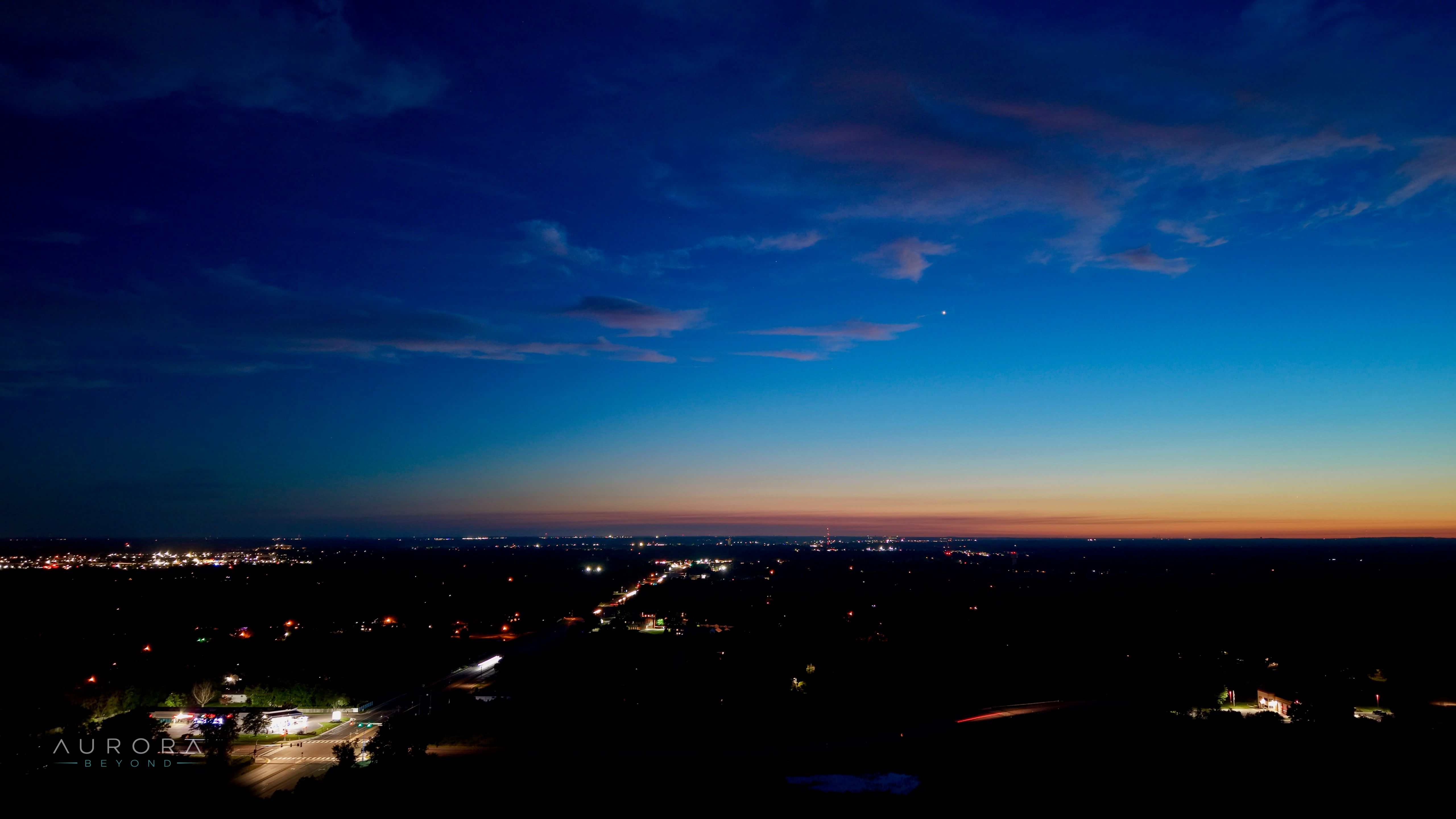 Deep blue dusk sky above a town beginning to light up