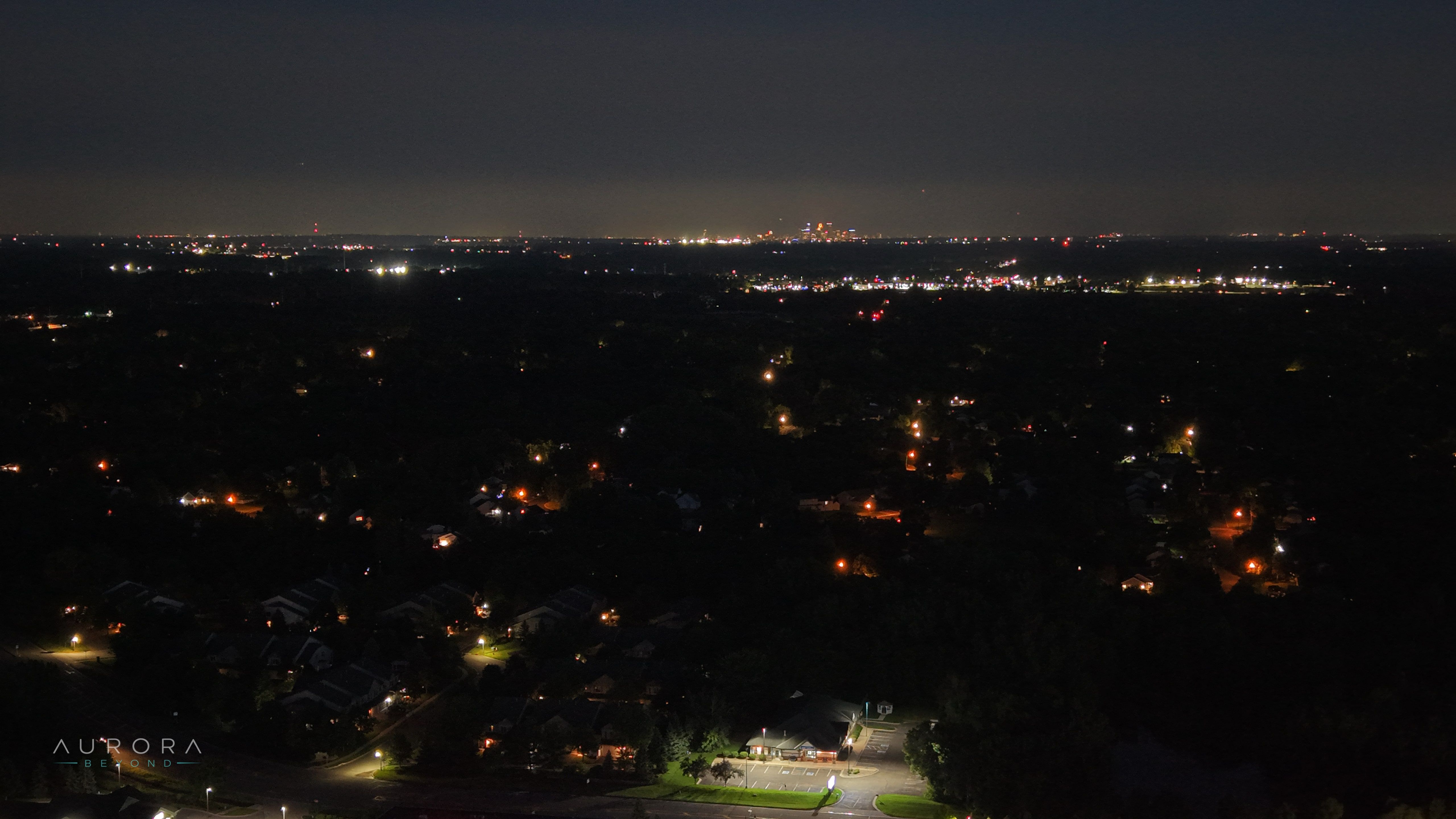 Streetlights scattered across a neighborhood at night, city glow on the horizon