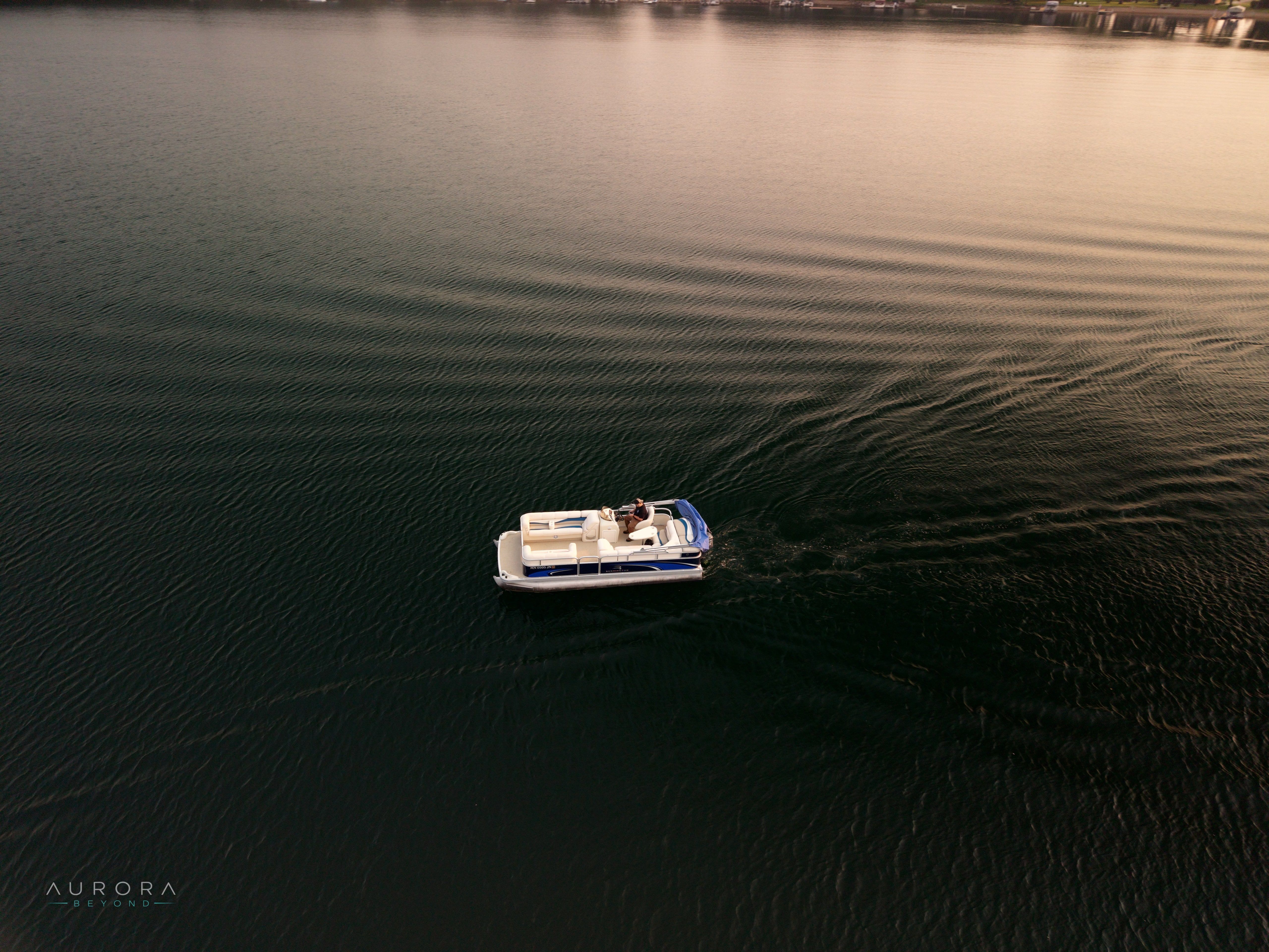 A pontoon boat on rippled water in low evening light
