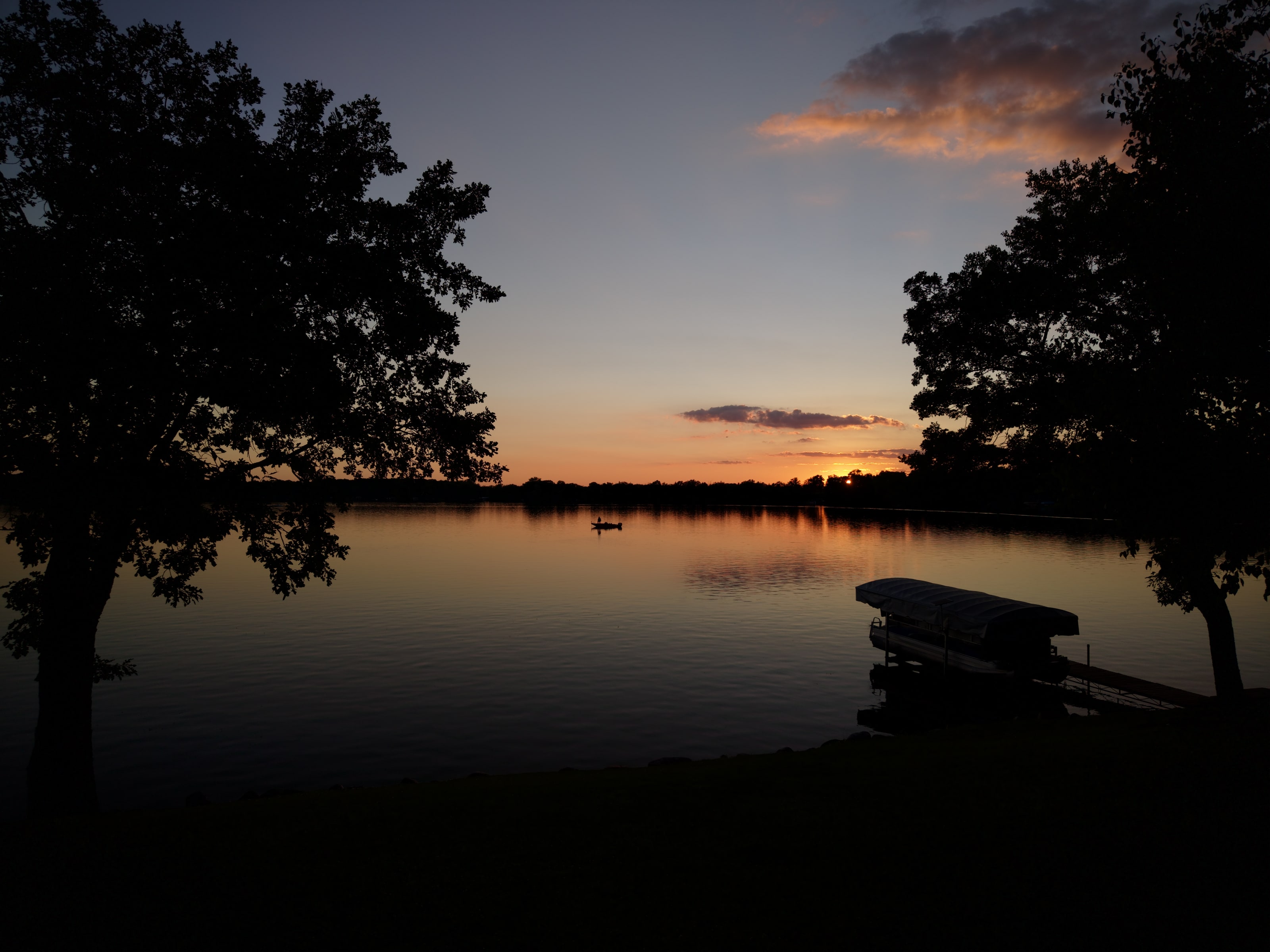 Sunset light over a lake with dock, shoreline, and quiet cabin-country landscape