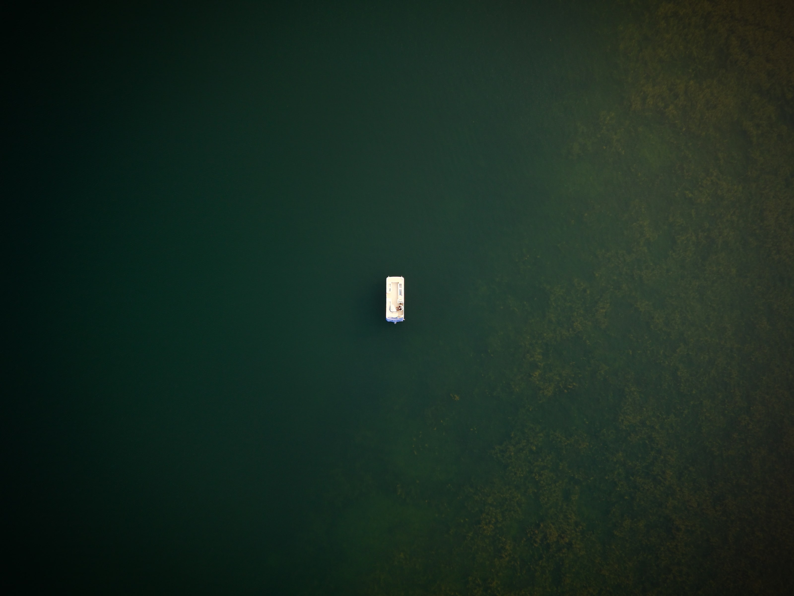 A lone boat seen from above in deep green northern water