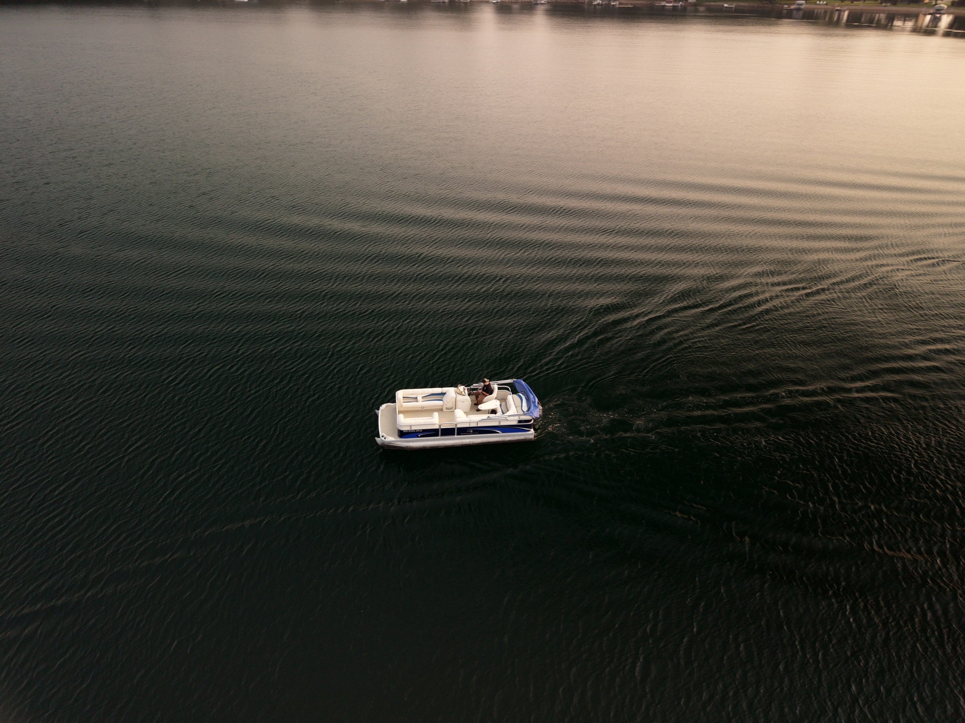 A boat moving across dark lake water in evening light